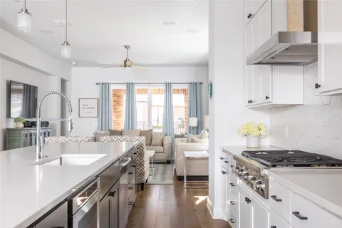a kitchen with stove a sink dishwasher and white cabinets with wooden floor