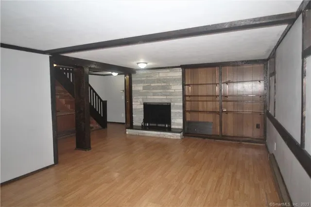 a view of empty room with wooden floor and fireplace