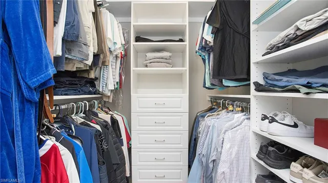 a view of walk in closet with clothes and shoes