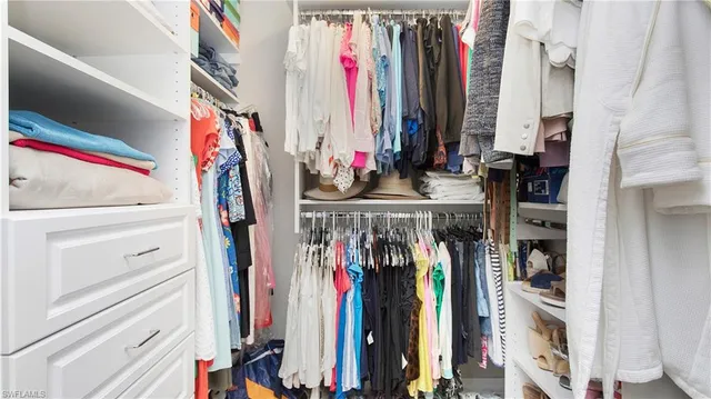 a view of walk in closet with clothes and shoes