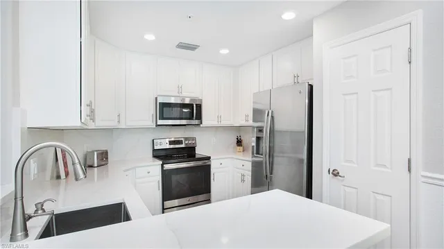 a kitchen with stainless steel appliances a refrigerator sink and white cabinets