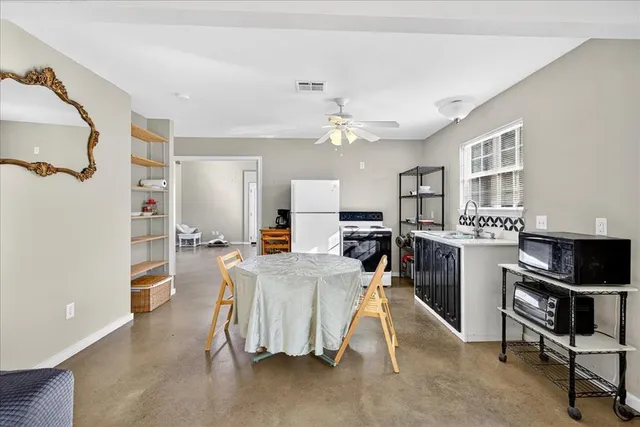 a view of a kitchen with kitchen island stainless steel appliances refrigerator stove dining table and chairs