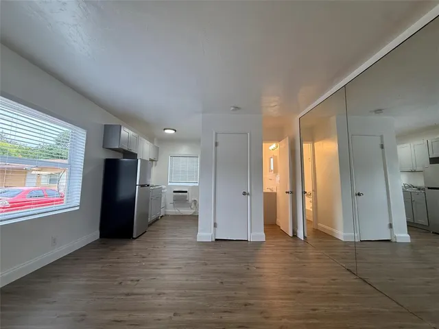 a view of an empty room with wooden floor and a window