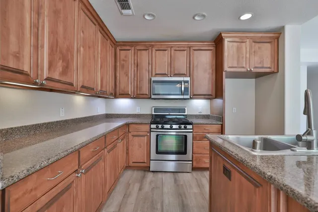 a kitchen with stainless steel appliances granite countertop a sink stove and refrigerator