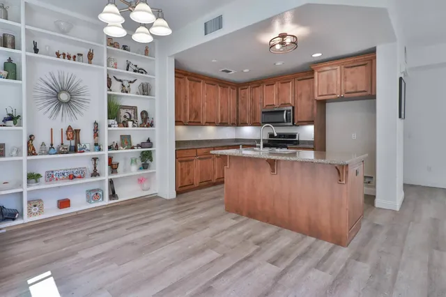 a kitchen with kitchen island a wooden floor stainless steel appliances and cabinets