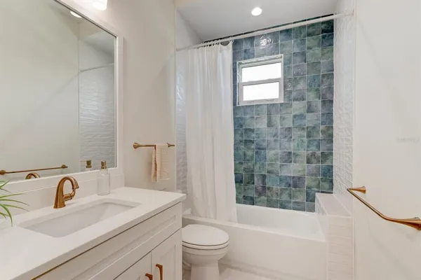a bathroom with a bathtub shower sink vanity mirror and toilet