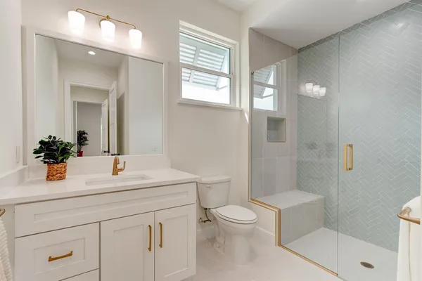 a bathroom with a sink a toilet a mirror and shower