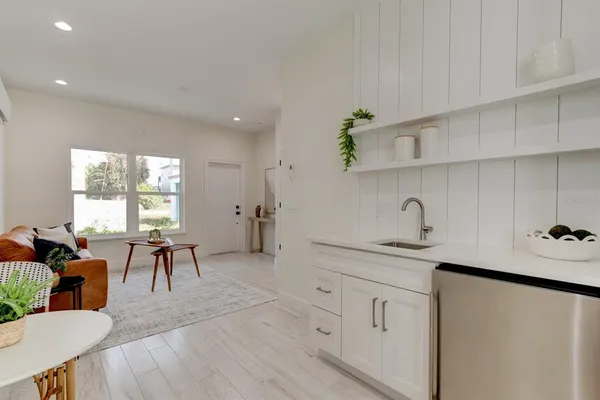 a very nice looking kitchen with granite countertop a stove a sink a dining table and chairs
