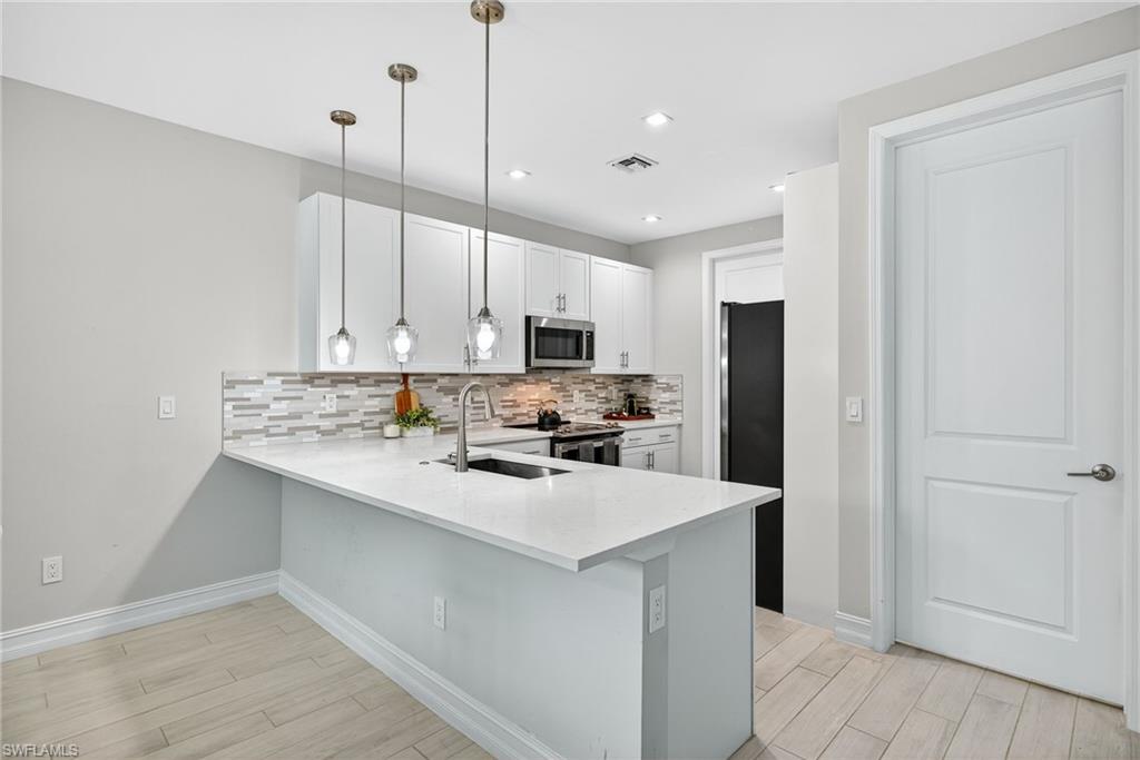 7570 Rockefeller Drive Naples, FL 34119 - Photo 12 of 34 a kitchen with a sink a refrigerator and white cabinets