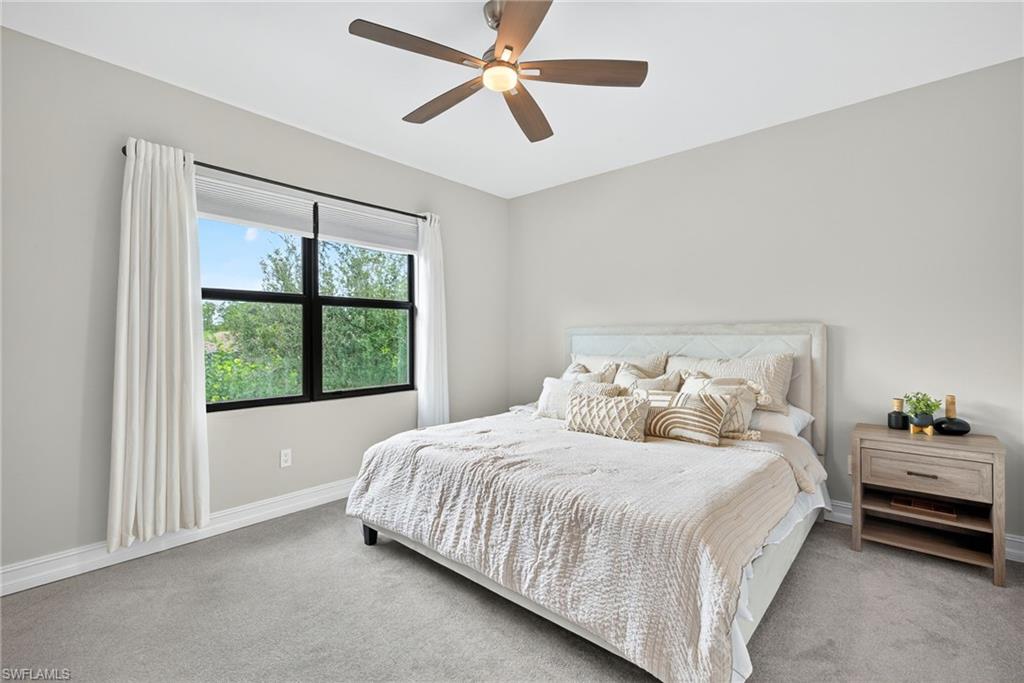 7570 Rockefeller Drive Naples, FL 34119 - Photo 13 of 34 a bedroom with a large bed and a chandelier fan