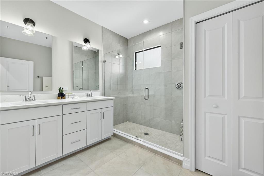7570 Rockefeller Drive Naples, FL 34119 - Photo 16 of 34 a bathroom with double sink and a mirror