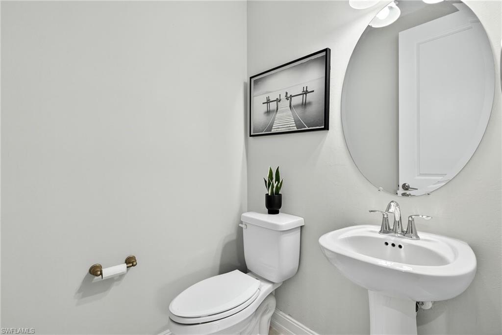 7570 Rockefeller Drive Naples, FL 34119 - Photo 20 of 34 a bathroom with a toilet a sink and mirror