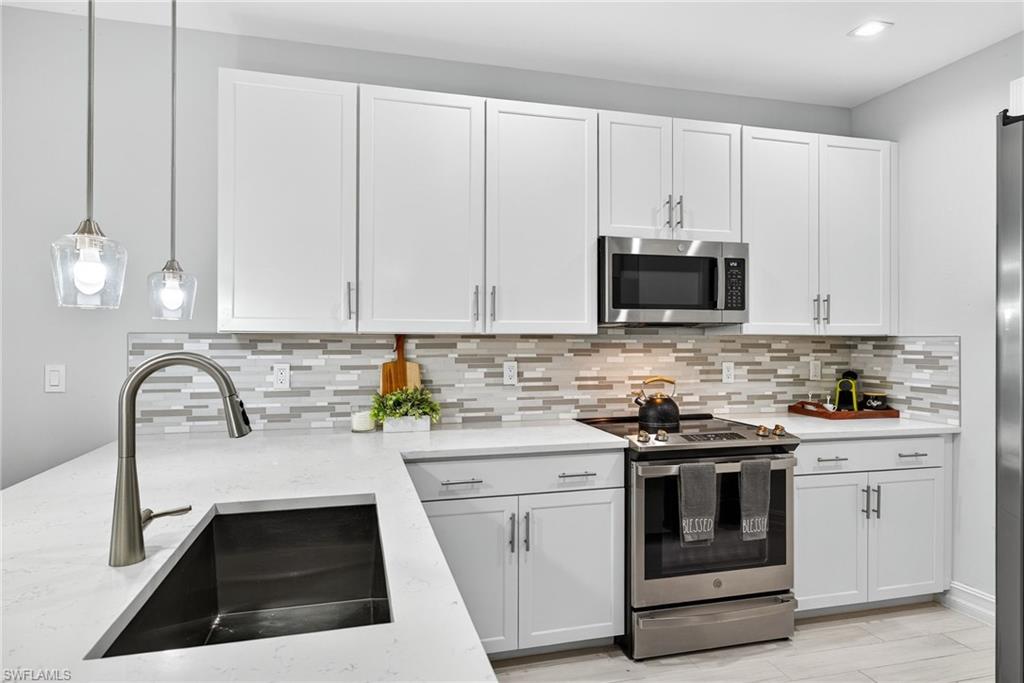 7570 Rockefeller Drive Naples, FL 34119 - Photo 3 of 34 a kitchen with white cabinets appliances and sink