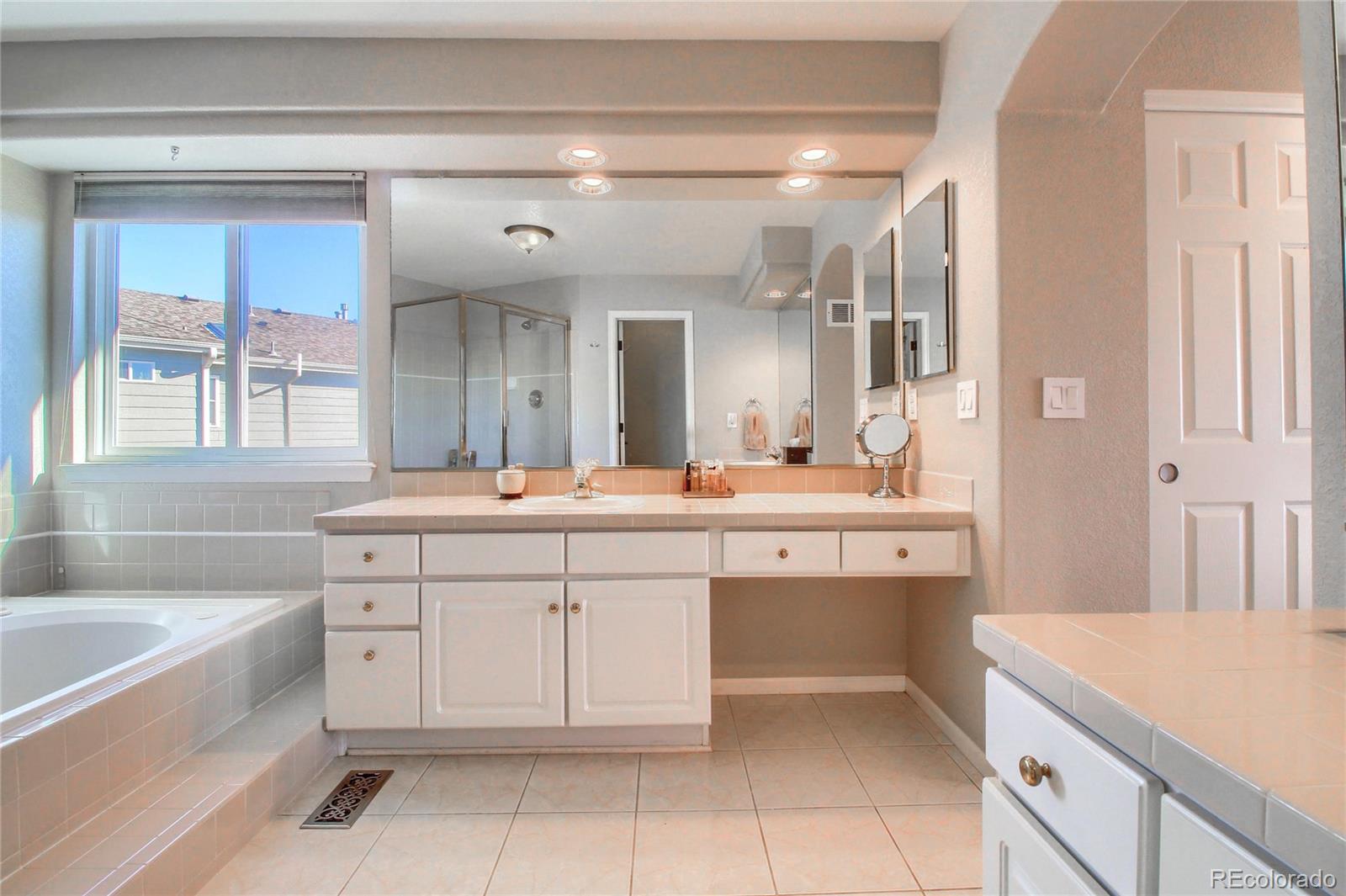 8952 Tuscany Lane Highlands Ranch, CO 80130 - Photo 18 of 32 a spacious bathroom with a sink a mirror a bathtub and next to a window
