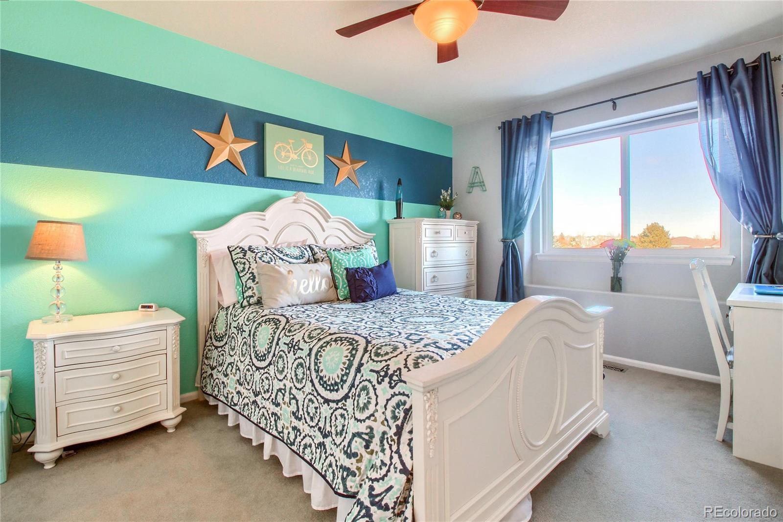 8952 Tuscany Lane Highlands Ranch, CO 80130 - Photo 21 of 32 a bedroom with a bed and a chandelier