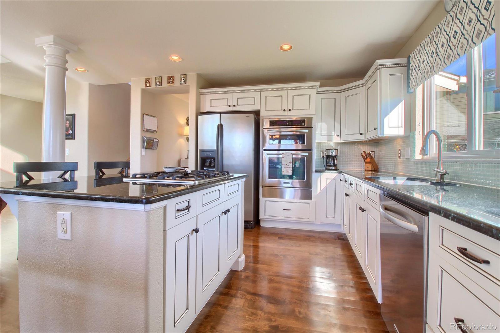 8952 Tuscany Lane Highlands Ranch, CO 80130 - Photo 8 of 32 a large kitchen with granite countertop a sink counter top space a stove and cabinets