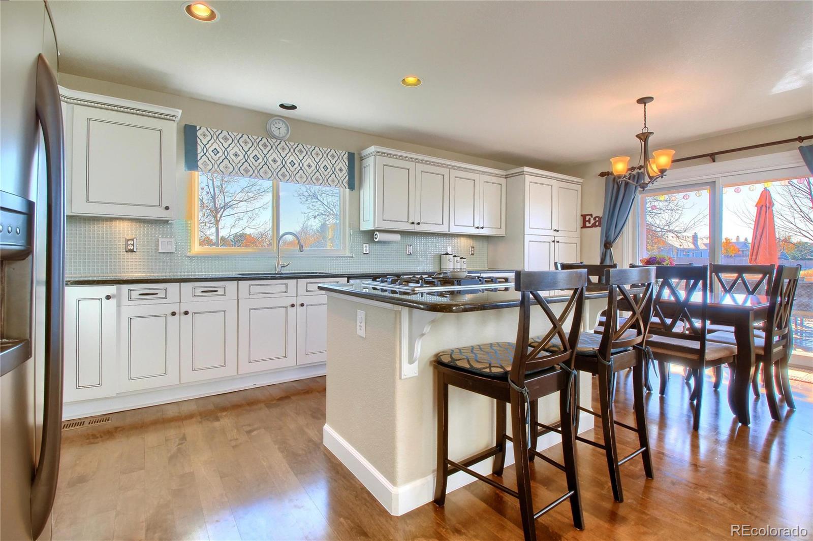 8952 Tuscany Lane Highlands Ranch, CO 80130 - Photo 9 of 32 a kitchen with granite countertop a table chairs stove and white cabinets