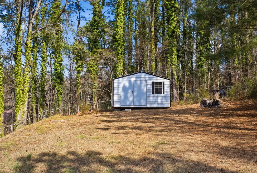 108 Hodge Street Abbeville, SC 29620 - Photo 26 of 39 A well-maintained shed offers practical outdoor storage amidst natural surroundings.