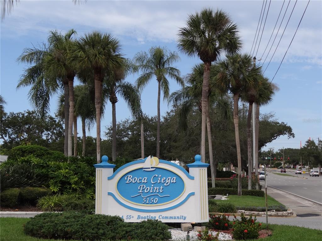 a sign board with a park area and a palm tree
