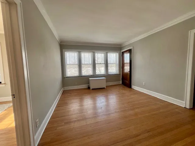 a view of an empty room with a window and wooden floor