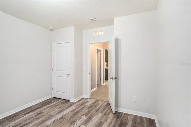 a view of a hallway with wooden floor and a bathroom