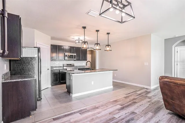 a kitchen with stainless steel appliances kitchen island granite countertop a refrigerator a stove a sink dishwasher a microwave oven with cabinets and wooden floor