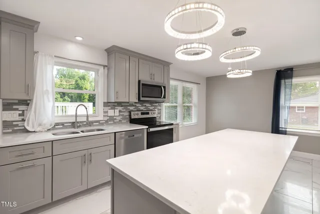 a kitchen with stainless steel appliances granite countertop a sink a stove a microwave cabinets and a window