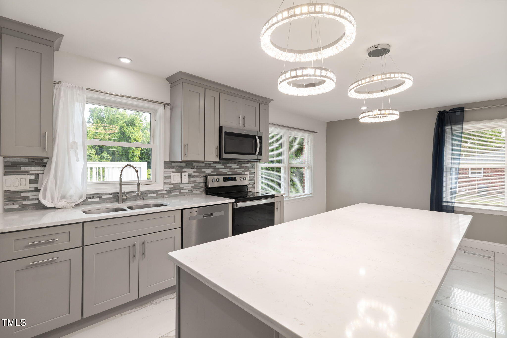 a kitchen with stainless steel appliances granite countertop a sink a stove a microwave cabinets and a window