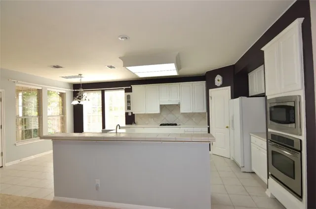 a kitchen with stainless steel appliances a refrigerator and a stove top oven