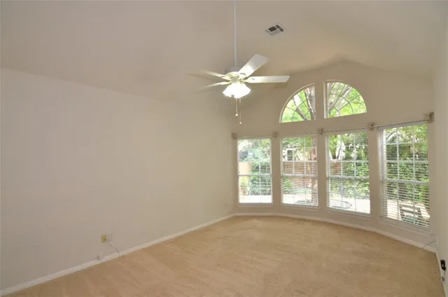 an empty room with windows and chandelier fan