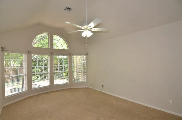 an empty room with windows and fan