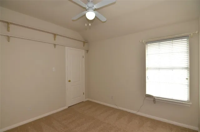 an empty room with a window and a fan