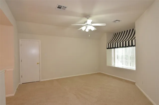 an empty room with windows and fan