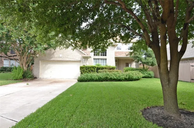 a front view of a house with a yard and a large tree