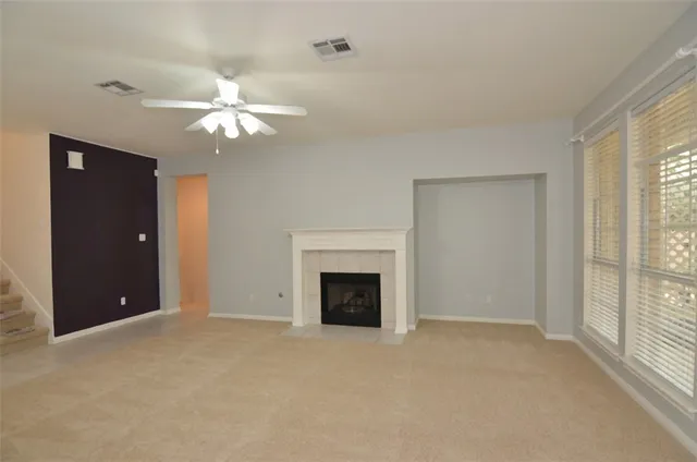 a view of a livingroom with a fireplace ceiling fan and windows