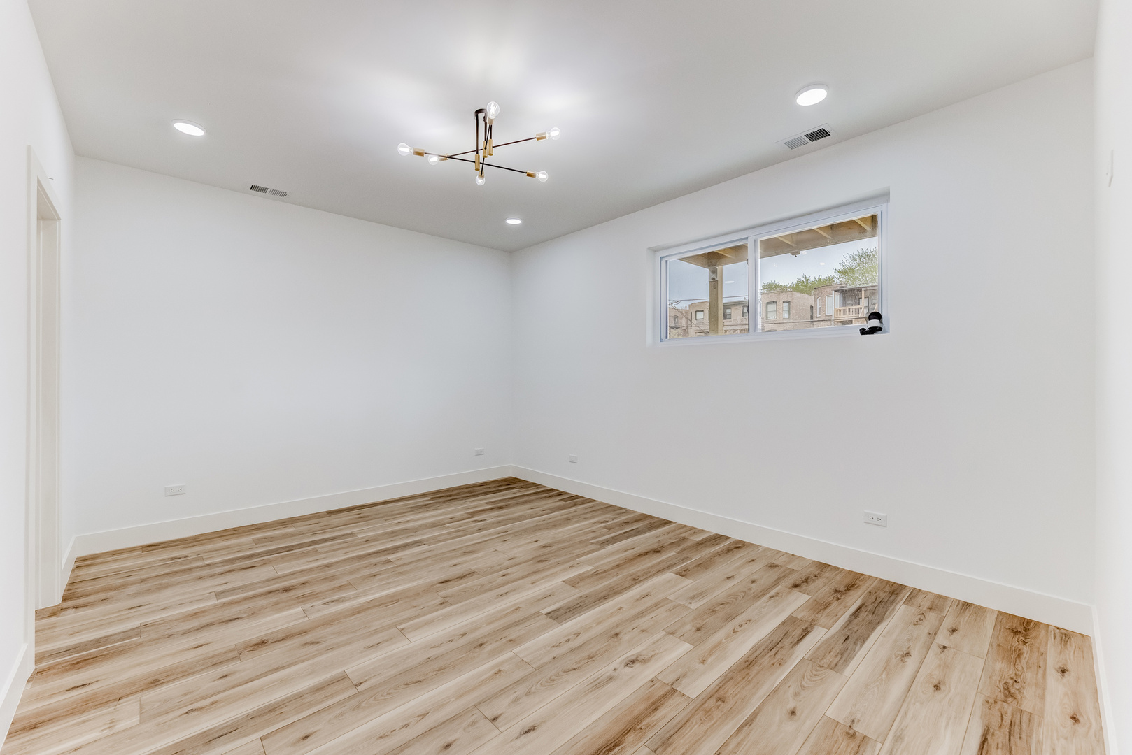 5921 South Calumet Avenue, Unit 2 Chicago, IL 60637 - Photo 18 of 40 an empty room with wooden floor chandelier fan and windows