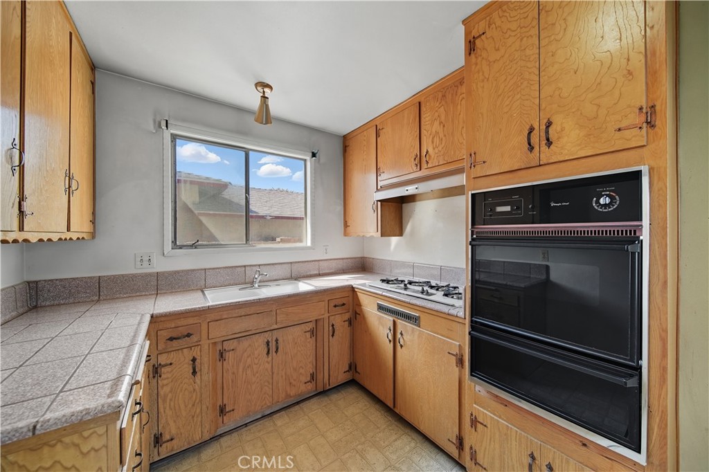 16402 Gridley Road Norwalk, CA 90650 - Photo 8 of 19 a kitchen with a sink stove and cabinets