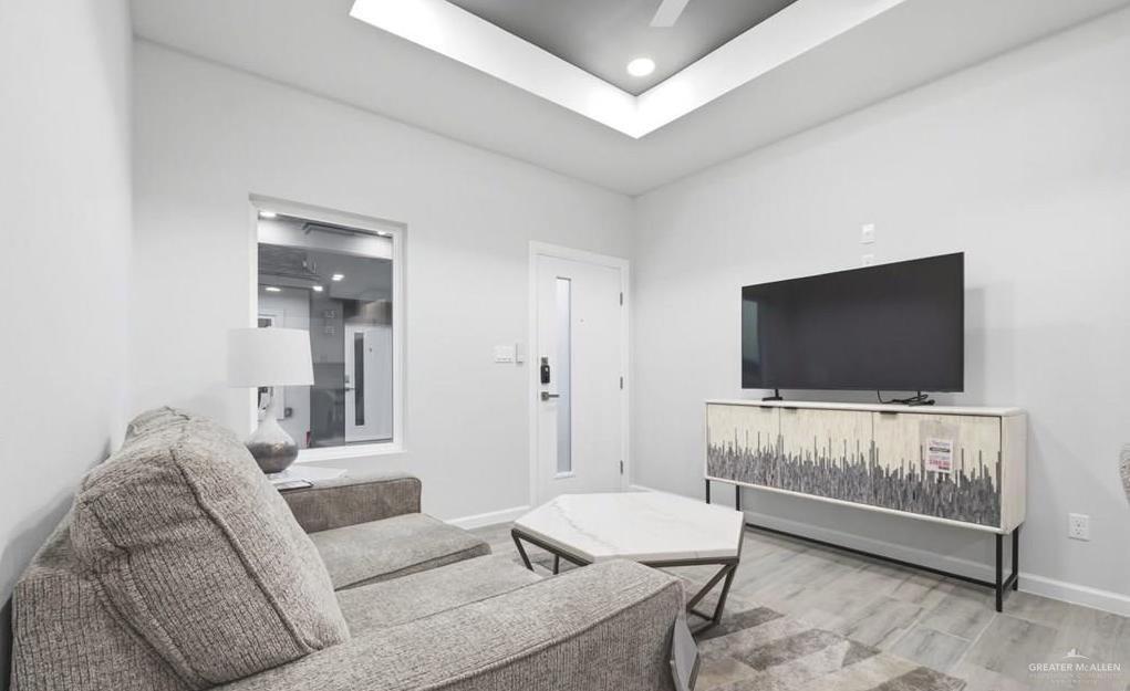 1604 Clinton Street, Unit 2 Harlingen, TX 78550 - Photo 5 of 14 Living area featuring light gray walls, a tray ceiling with recessed lighting, and wood-finish flooring
