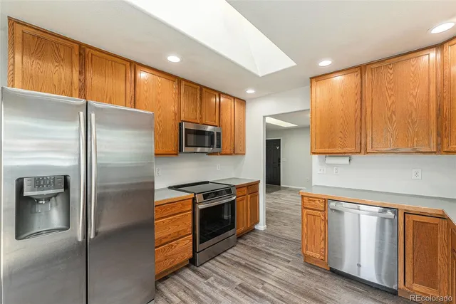 a kitchen with stainless steel appliances granite countertop a refrigerator a stove and a sink with wooden floor