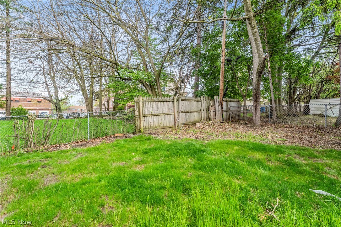18155 Libby Road Maple Heights, OH 44137 - Photo 30 of 32 Expansive green space featuring chain-link fencing, a wood privacy fence, and mature trees