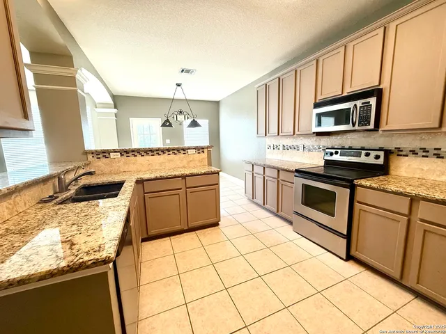 a kitchen with stainless steel appliances granite countertop a stove sink and cabinets