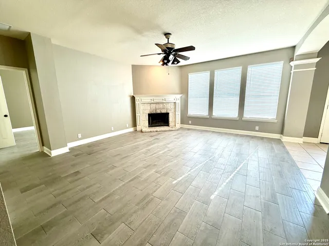 a view of a livingroom with a fireplace a ceiling fan and front door