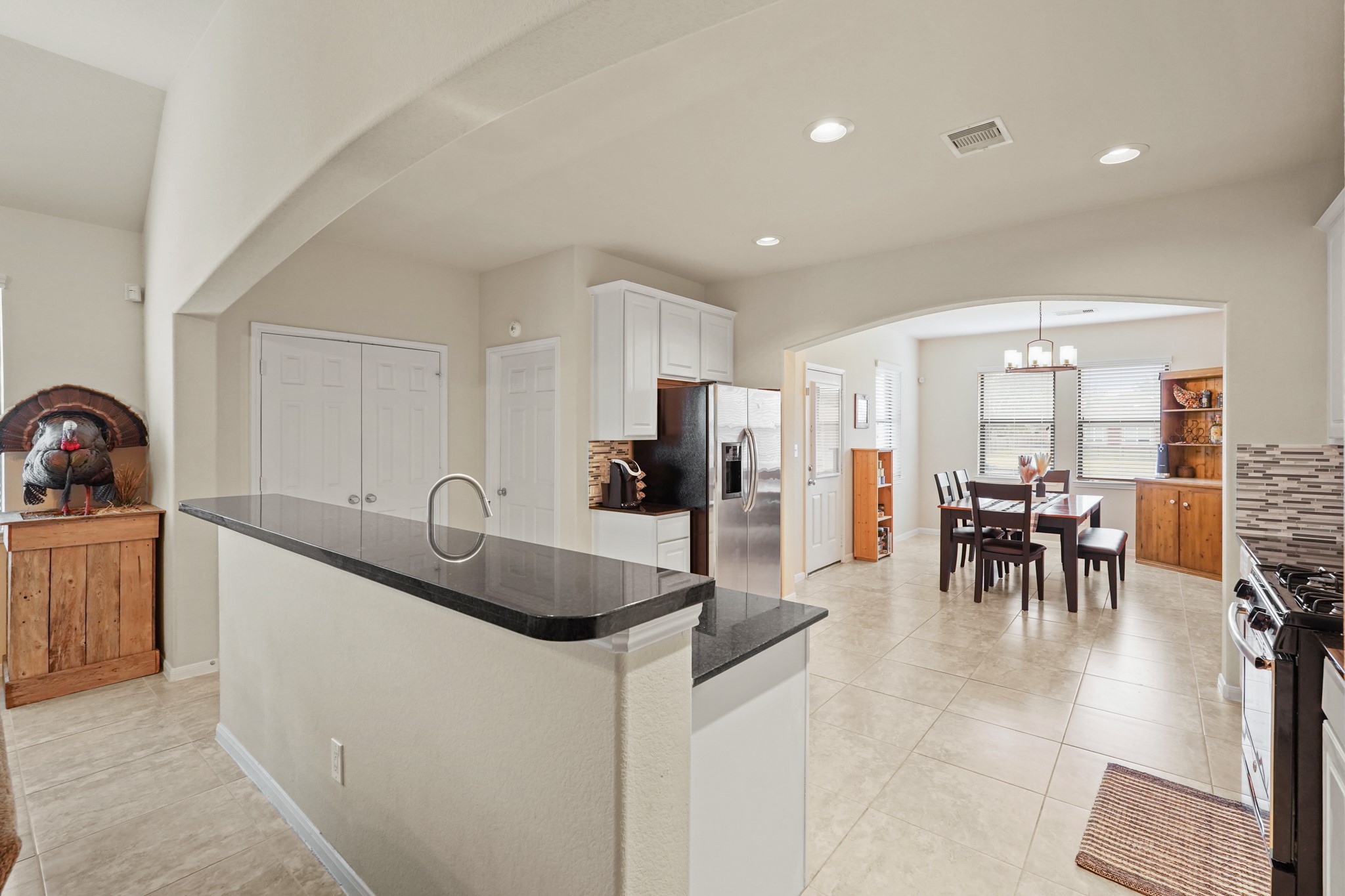 2027 Wembley Way Rosenberg, TX 77471 - Photo 12 of 28 a kitchen with stainless steel appliances granite countertop a dining table chairs and white cabinets