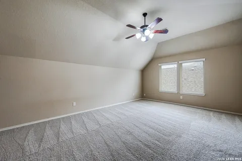 a view of an empty room with chandelier fan and fire place