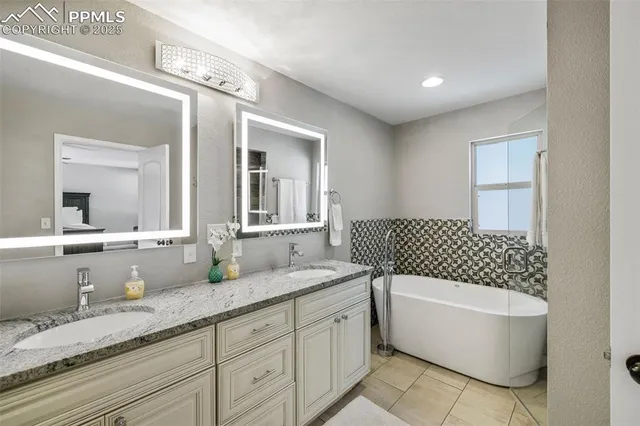 a bathroom with a granite countertop double vanity sink mirror and bathtub