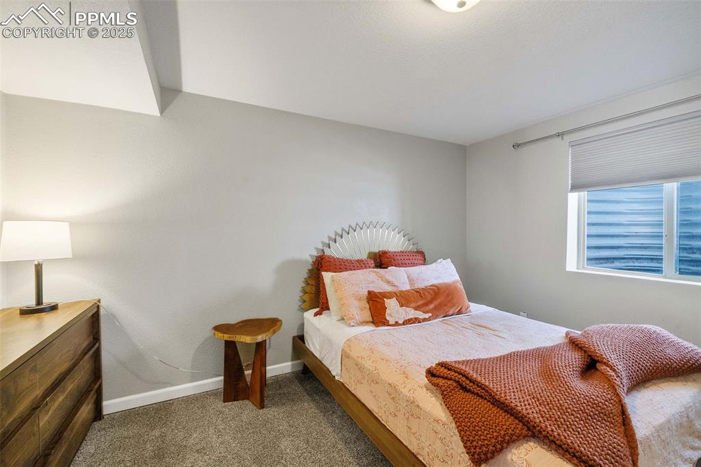 6940 Franciville Road Colorado Springs, CO 80908 - Photo 30 of 40 a bedroom with a bed and a lamp on table