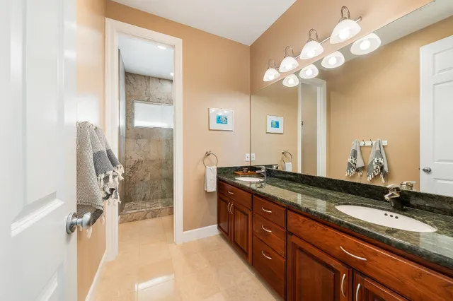 a spacious bathroom with a granite countertop sink a mirror and a shower