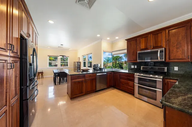 a kitchen with stainless steel appliances granite countertop a stove top oven a sink and a refrigerator