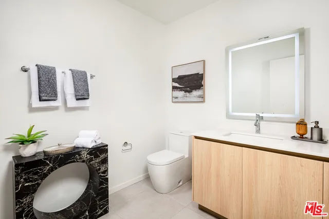 a bathroom with a granite countertop toilet sink and mirror