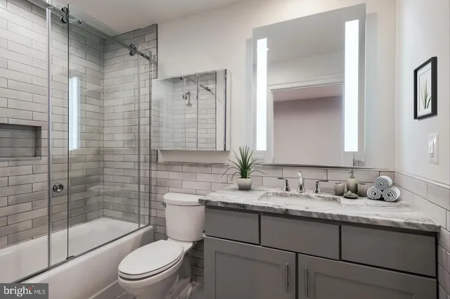 a bathroom with a granite countertop sink a toilet and shower
